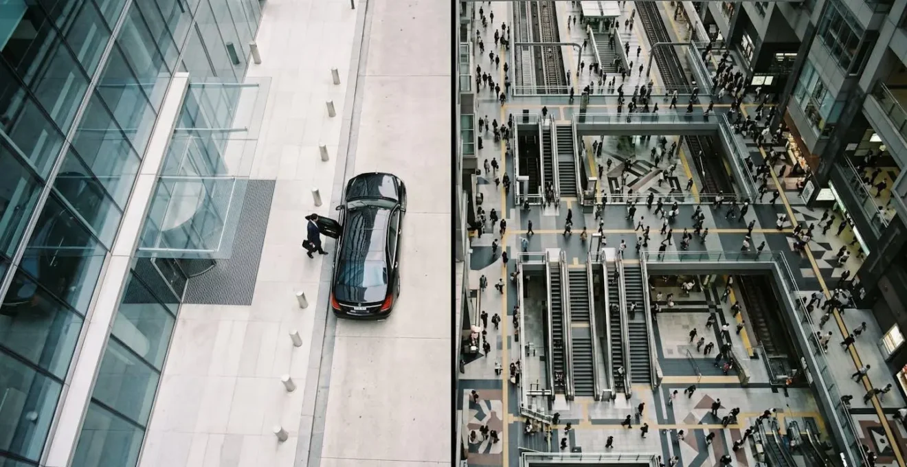 Overhead view of executive being collected from office entrance versus crowded train station concourse