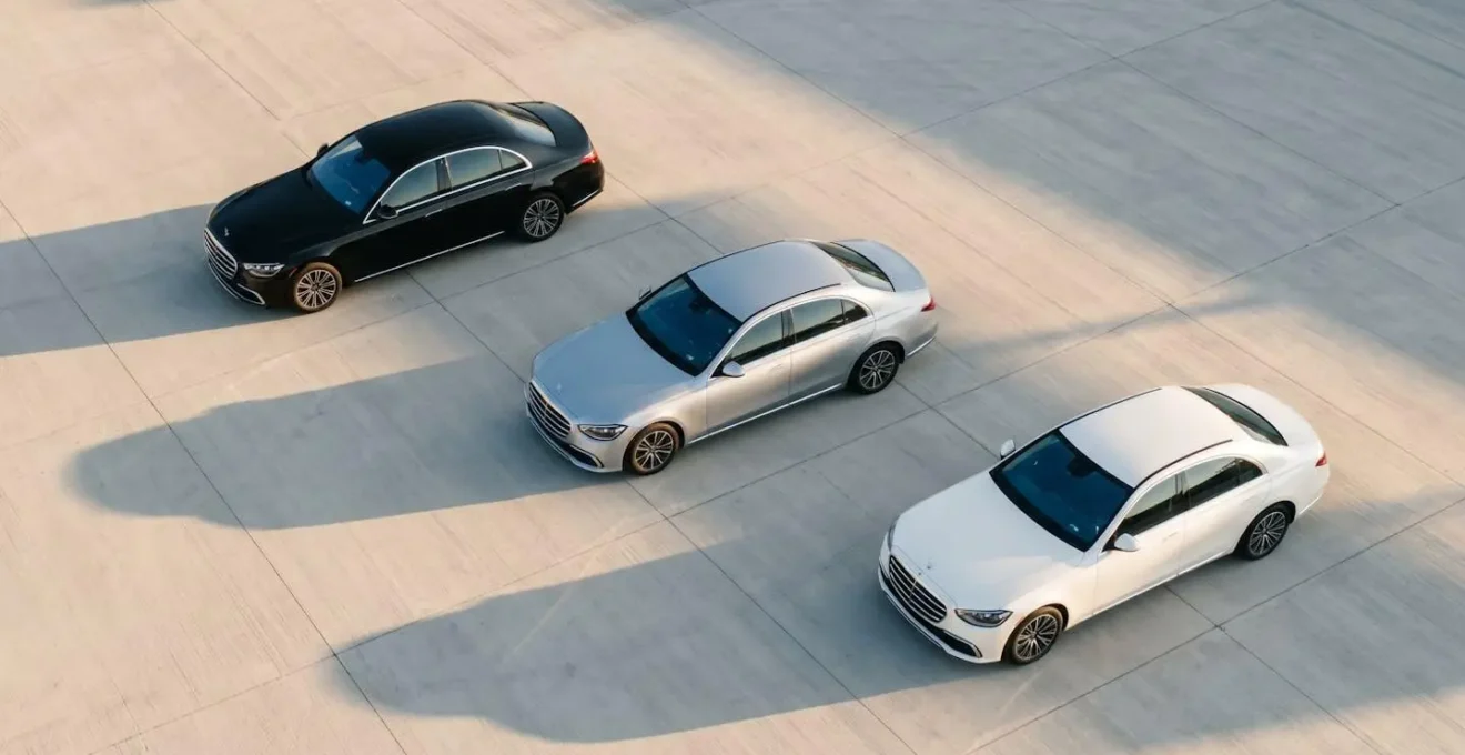 Three luxury sedans in black, silver and white parked in diagonal formation