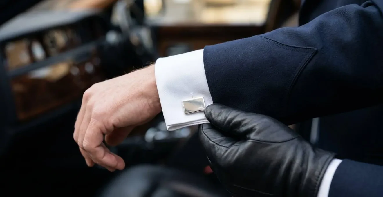 Professional chauffeur in formal attire beside luxury vehicle