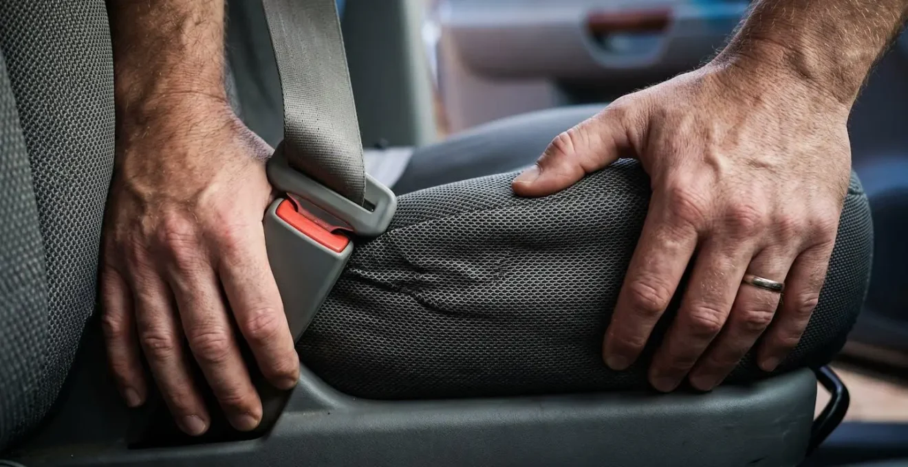 Hands demonstrating proper wiggle test technique on car seat base